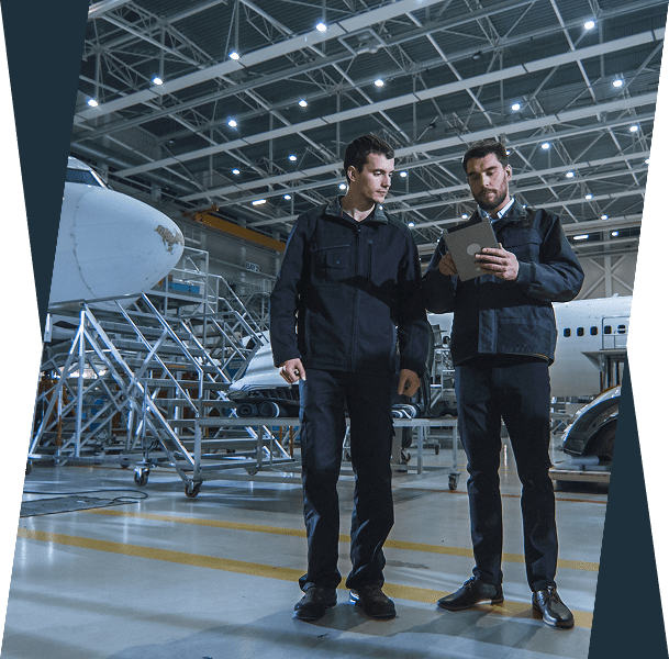 Two technicians inspecting tablet in airplane hangar.