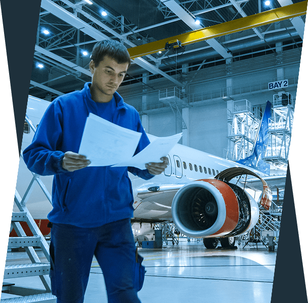 Man inspecting documents near airplane in hangar.