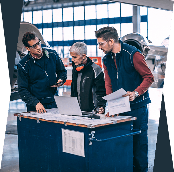 Aircraft technicians discussing plans in hangar.