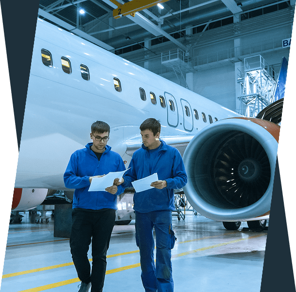 Technicians reviewing documents near airplane engine.