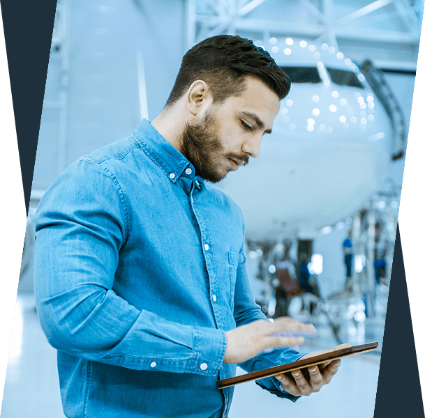 Man using tablet in airplane hangar.