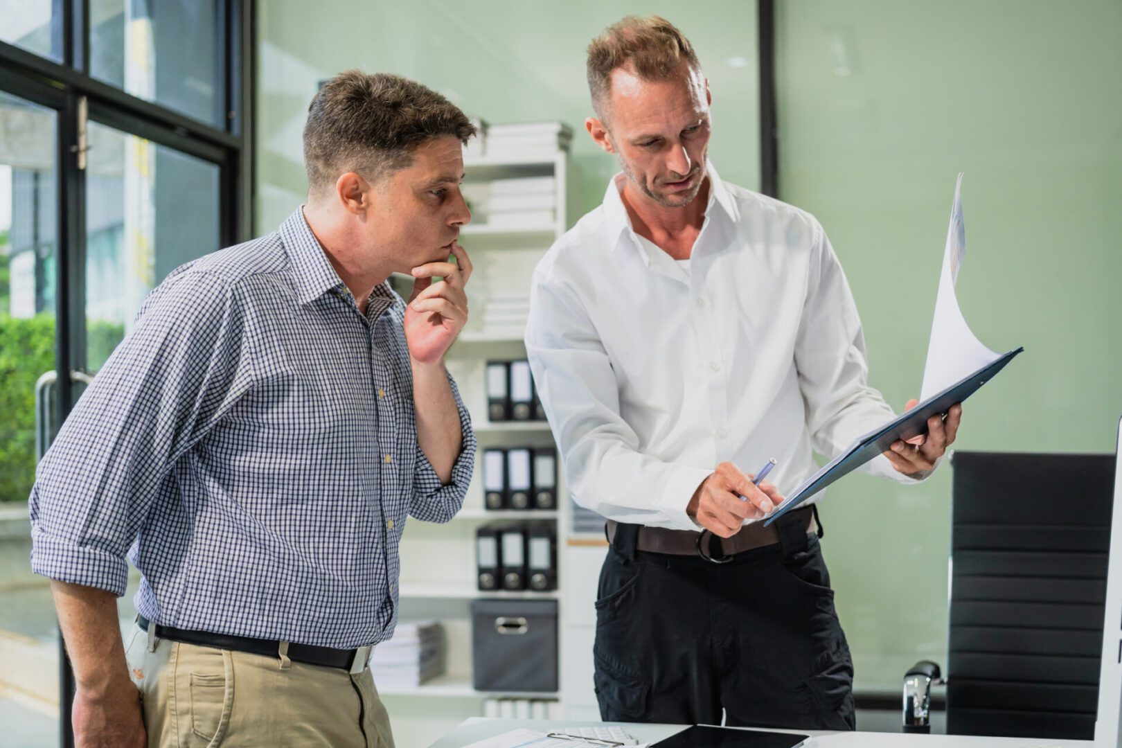 Two men discussing documents in office.