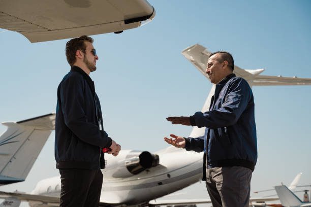 Two men discussing near a private jet on a sunny day.